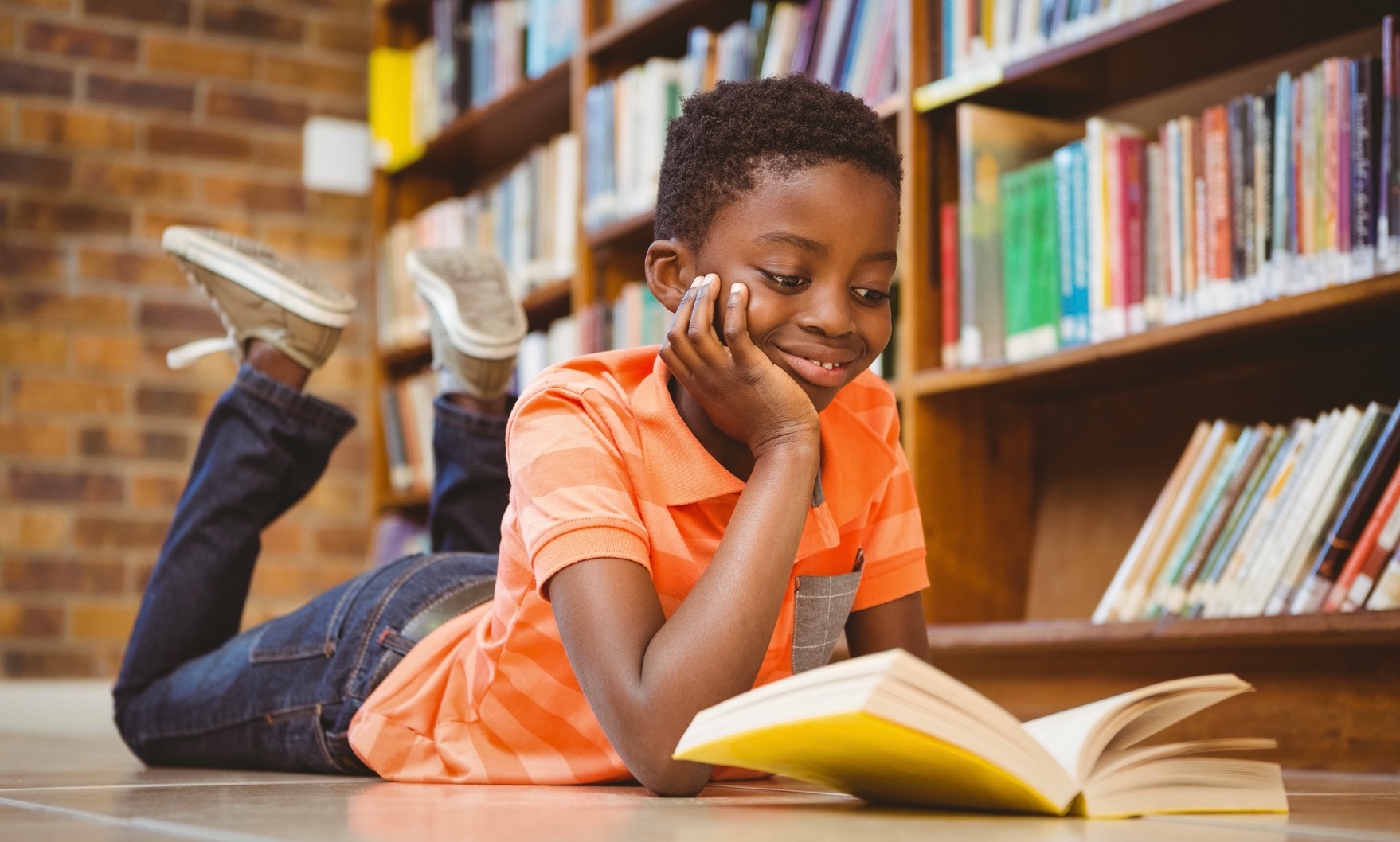 young boy reading in library